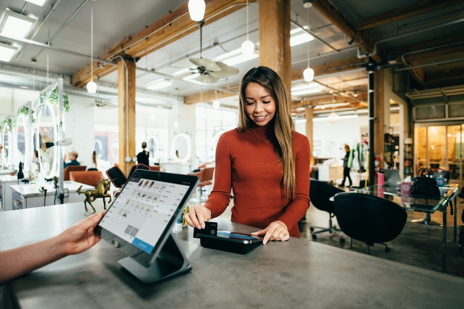 A salon owner taking a card payment at her counter — the kind of business we help get found online